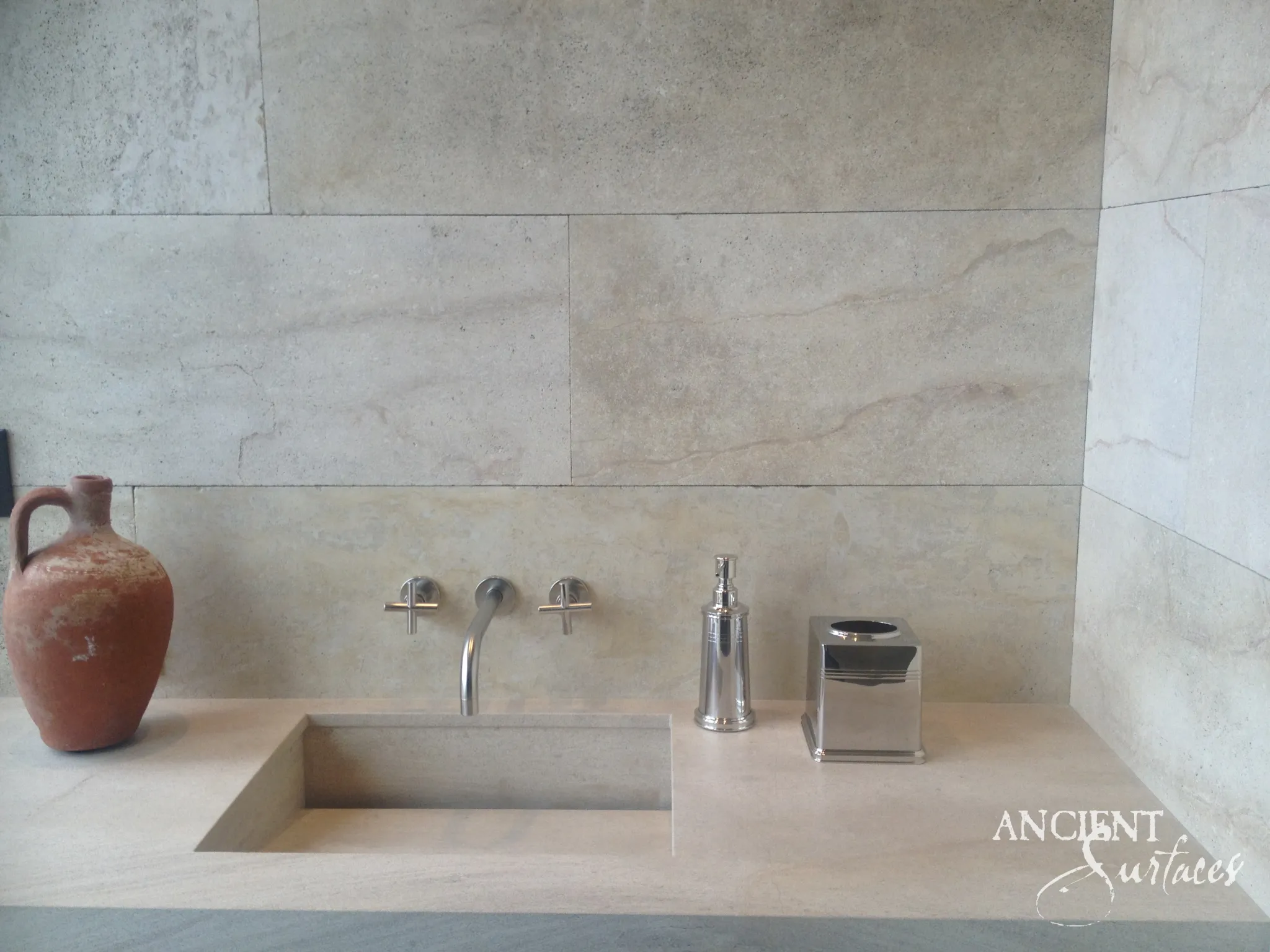 Rectangular ramp basin cut into a honed reclaimed limestone slab countertop with a chrome faucet