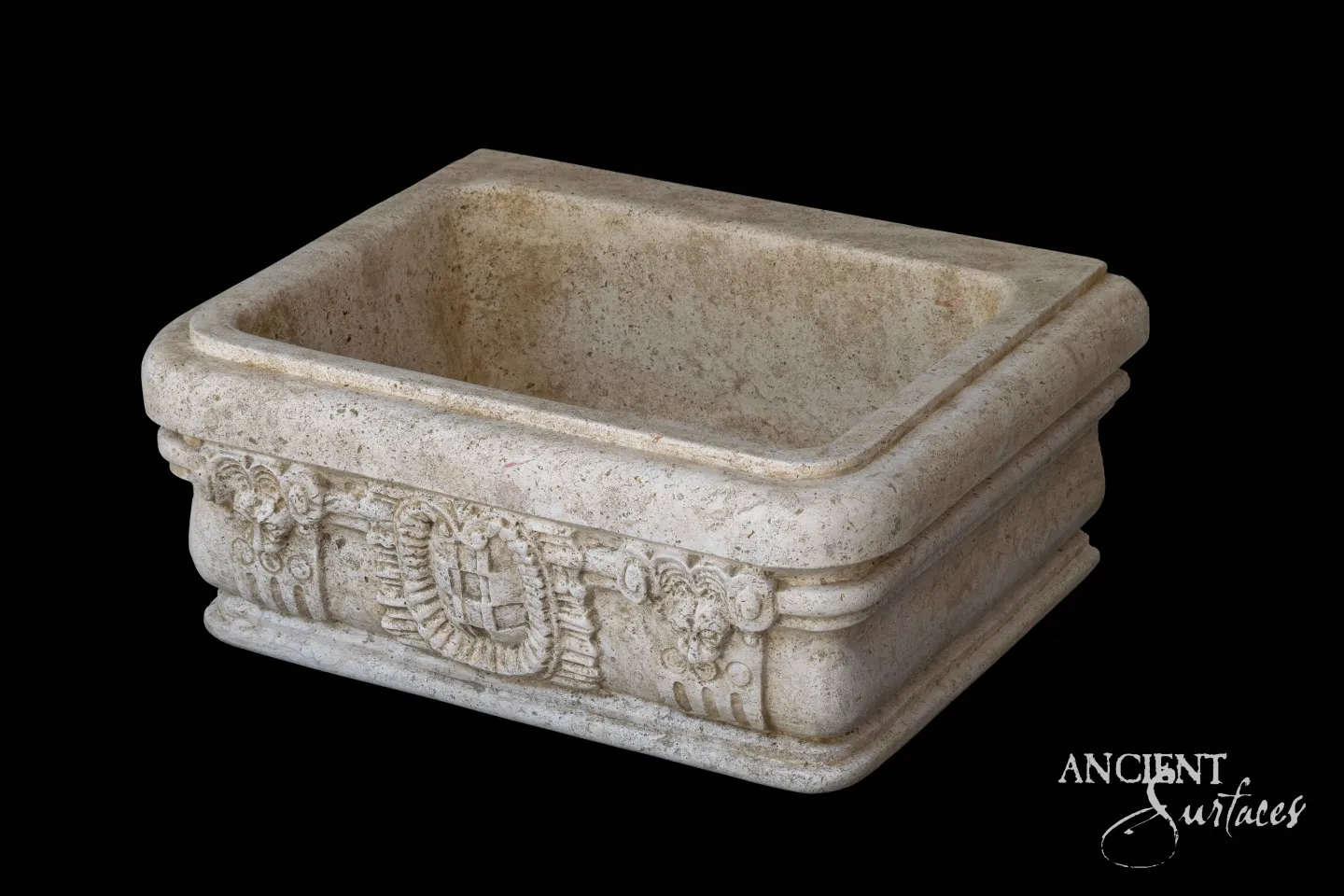 Small carved reclaimed limestone vessel sink with a laurel garland and mask motif on the front