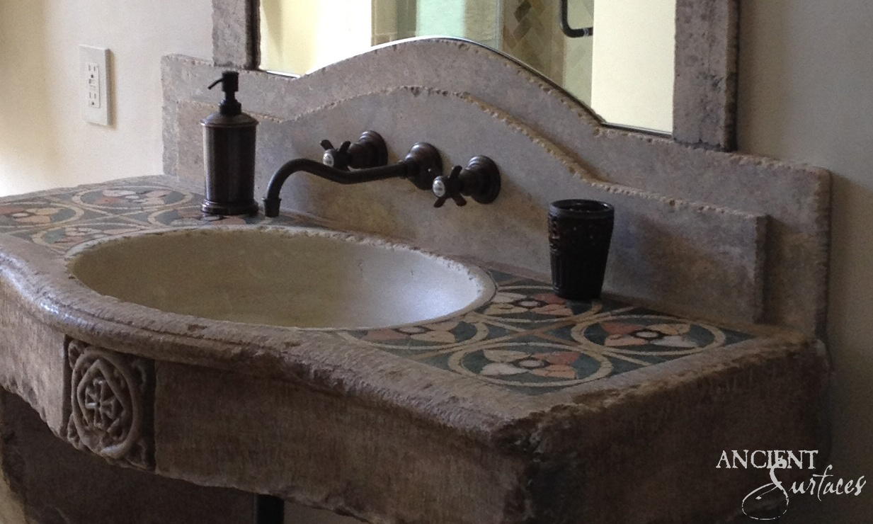 Reclaimed limestone sink with a patterned tile-inlaid deck, carved backsplash and oil-rubbed bronze faucet